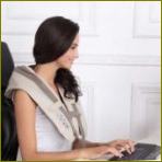 Ein Mädchen, das an einem Computer mit einem Schultermassagegerät arbeitet