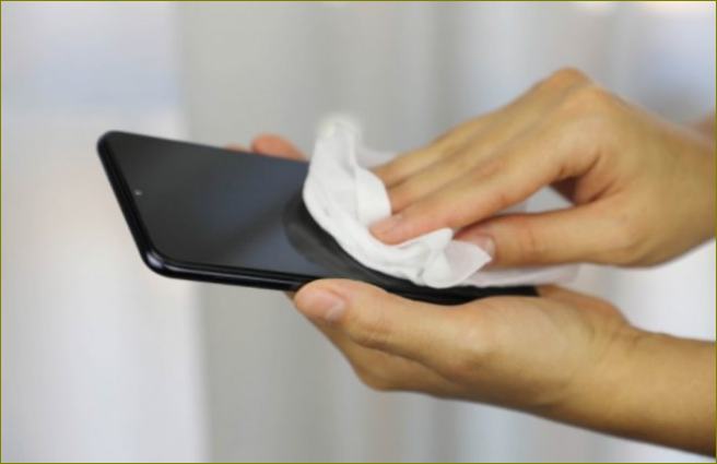 Abwischen des Smartphones mit einem Taschentuch