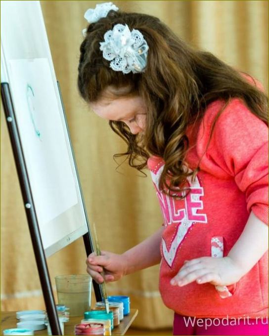Das kleine Mädchen malt mit Farbe auf einer Staffelei